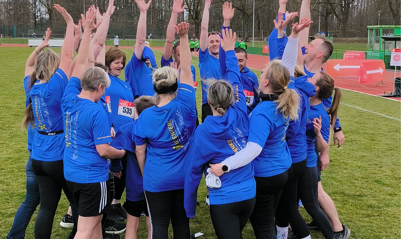 Mitarbeiter der Bruno Nebelung GmbH im Team-Huddle mit Händen in der Mitte vor dem Firmenlauf